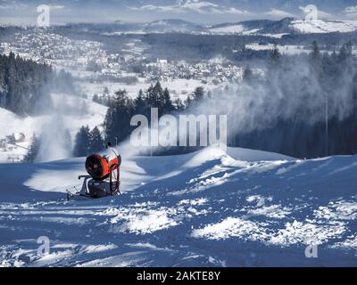 Schneemaschine, auch Schneekanone oder Schneekanone im Einsatz genannt. Bialka Tahrzanska Skigebiet in Polen im Hintergrund Stockfoto