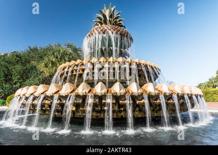 Malerische Aussicht auf das Wasser, das von einem Brunnen in Form einer Ananas an einem blauen Himmelnachmittag an der Küste in Charleston, South Carolina, USA, strömt Stockfoto