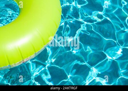 Farbenfroher Poolring, der auf türkisfarbenem Wasser in tropischer Sonne schwebt Stockfoto