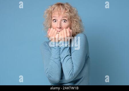 Nervös, reife Frau beißt Fingernägel, ängstlich fühlen, afraids von Ärzten, Ausdruck hat Angst, Sorgen, jemand ihr Geheimnis kennen. Studio shot Stockfoto