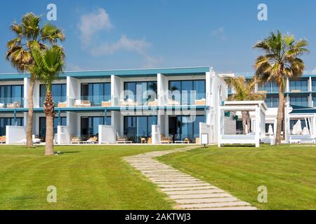 Modernes Gebäude am Meer mit Palmen und grünen Rasen Stockfoto