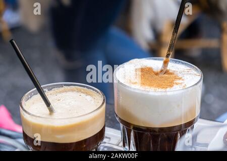 Freddo Espresso und Capuccino. Ein paar hohe Gläser mit kaltem Kaffee und schwarze Strohhalme für ein Paar. Zeit sich zu entspannen. Nahaufnahme, blur Bac Stockfoto