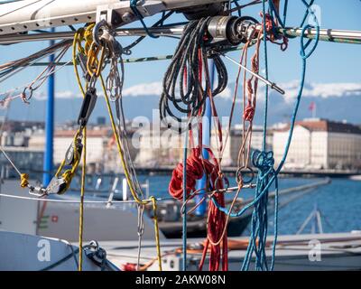 Seile und Segellinien hängen von einem Bootsmast ab. Die bunten Seile bilden an einem Sommertag einen schönen Hintergrund vor einem blauen See und Himmel. Stockfoto