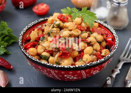 Garnitur von Kichererbsen mit Paprika und Tomaten, ein vegetarisches Gericht reich an Protein, bei einer Platte gegen einen dunklen Hintergrund horizontal entfernt Stockfoto