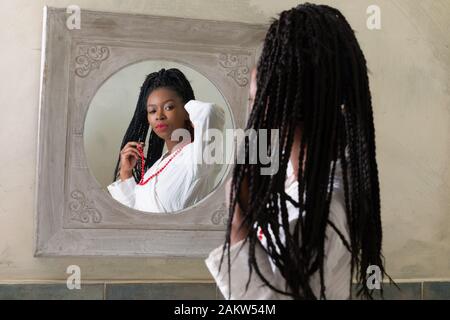 Hübsche junge afrikanische amerikanische Frau, die Ihre morgendliche Routine zu tun vor dem Badezimmerspiegel Stockfoto