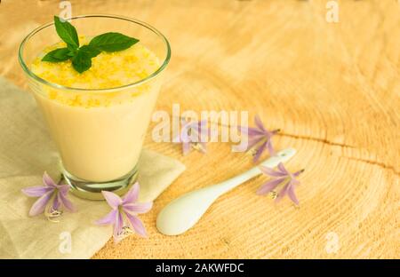 Vanille Mousse oder Pudding mit Zitronenschale und Minze im Glas Schale dekoriert. Close-up. Stockfoto