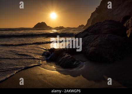 Die untergehende Sonne über Seal Rock entlang der kalifornischen Küste von San Francisco, während die Wellen an einem klaren Nachmittag einrollen Stockfoto