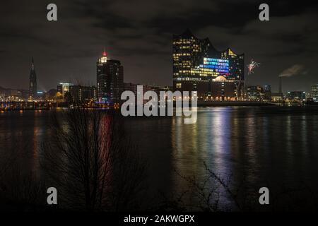 Nachtaufnahme der beleuchteten Elbphilharmonie im Hamburger Hafen in der Hafenstadt an der Elbe mit einigen Reflexionen im Wasser Stockfoto