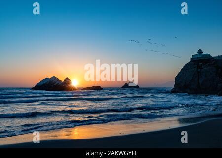 Die untergehende Sonne über Seal Rock entlang der kalifornischen Küste von San Francisco, während die Wellen an einem klaren Nachmittag einrollen Stockfoto