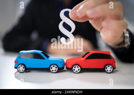 Rechtsanwalt hält zwei kleine Autos in der Hand und Absatz Zeichen Stockfoto