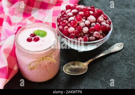 Gesunder Joghurt aus gefrorenen Preiselbeeren auf schwarzem Hintergrund. Das Konzept gesunder Desserts. Ansicht von oben. Stockfoto
