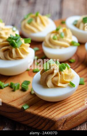 Russische Eier mit grünen Zwiebeln auf rustikalen Holzmöbeln Hintergrund, Ostern party Snack, Nahaufnahme Stockfoto