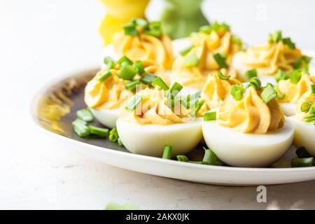 Verzierte Eier in rustikaler Keramikplatte, Osterparty-Imbiss, Nahaufnahme Stockfoto