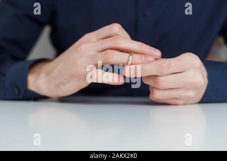 Der junge Mann nimmt den Hochzeitsring ab. Nahansicht. Scheidungskonzept. Stockfoto