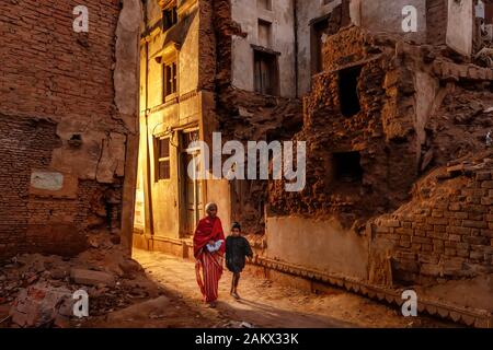 VARANASI, Indien, 19. JANUAR 2019: Eine bescheidene alte Frau und ein Kind sind zu Fuß in der Nacht in einem zerstörten Gegend der Stadt. Stockfoto