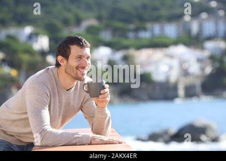 Glückliche Menschen trinken Kaffee, Blick in einen Balkon am Strand an einem sonnigen Tag Stockfoto