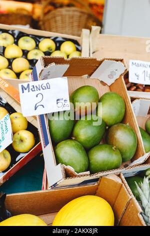 Frische rohe, unbehackte Mango-Tropenobst in Box zum Verkauf auf dem Bauernmarkt. Veganes Essen und gesundes Ernährungskonzept. Stock Foto grün Mango Stockfoto