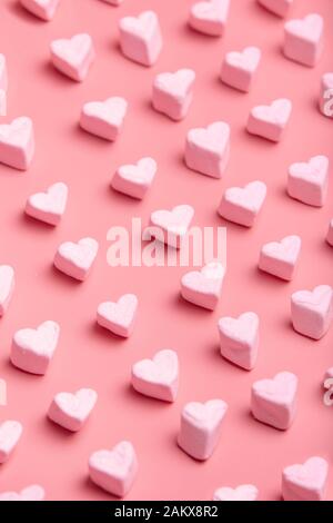 Herzförmige Süßigkeiten-Wolkenmuster auf pinkfarbenem Hintergrund. Vertikales Bild Valentinstag. Stockfoto