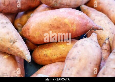 Frisches rohes biologisches Süßkartoffelgemüse als Hintergrund. Süßkartoffel zum Verkauf auf dem Bauernmarkt. Veganes Essen und gesunde Ernährung. Stock-Foto Stockfoto
