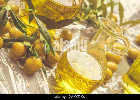 Extra natives Olivenöl Glas Oliven und Oliven Äste auf einem Tisch im Sommer. Stockfoto