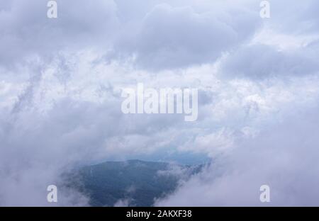 Wolken und Nebel sind über die ganze Stadt verstreut, durchziehen Lücken und sehen als grüne Berge. Stockfoto