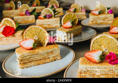 Leckere scheiben Honig Kuchen mit frischen Erdbeeren und frische Blumen auf einem Teller bereit zu dienen. Stockfoto