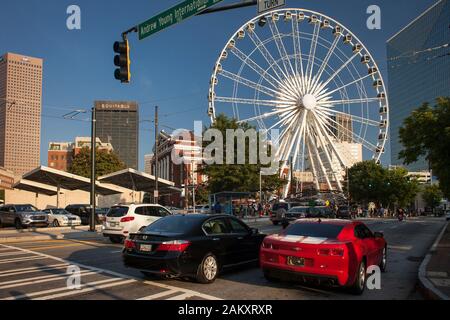 Horizontaler Schuss des Centennial Olympic Park Dr mit zwei Autos vorne und dem Skyview Atlanta Ferris Rad hinten, Atlanta, USAGeorgia, Stockfoto