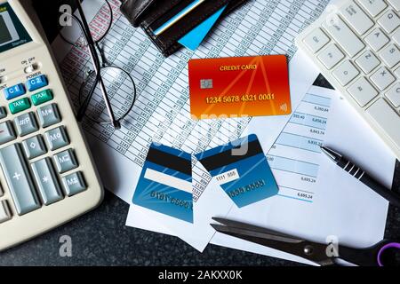 Halbieren Sie die Kreditkarte auf einem Schreibtisch mit einer Bankeinlage neben einer Computertastatur und einem Taschenrechner Stockfoto