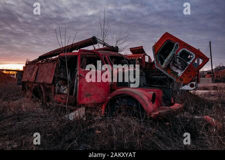 Alter verrostter zerbrochener verlassener sowjetischen Feuerwehrwagen bei Sonnenuntergang am Abend. Stockfoto