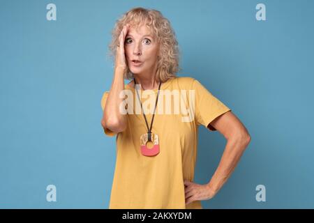 Traurige Frau mittleren Alters, die an Kopfschmerzen leidet und die Hand auf der Stirn hält. Stockfoto