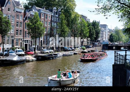 Im Sommer haben die Leute Spaß mit ihren Booten in den Kanälen von Amsterdam, Niederlande. Stockfoto