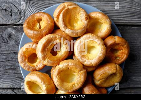 Nahaufnahme hausgemachter Yorkshire Puddings auf einem Teller auf einem rustikalen Holztisch, englische Küche, Blick von oben, Flachlage, Makro Stockfoto