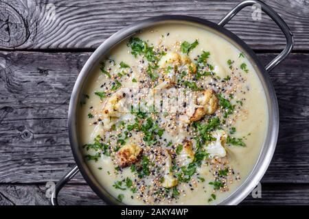 Cremig geröstete Knoblauchkröte mit asiago-käse und einer knusprig geknallten Quinoa und chia, die in einem Stocktopf auf einem rustikalen Holztisch, ho, toppen Stockfoto