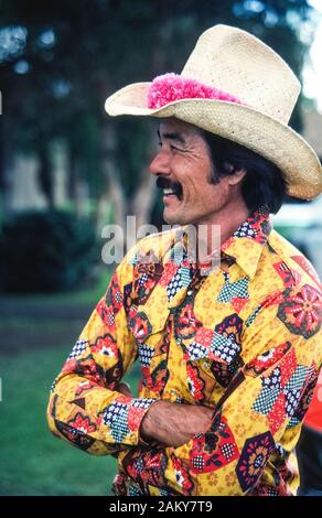 Trägt ein schickes Hemd und eine rosa Blume lei Um seinem Strohhut, eine hawaiische Paniolo (Cowboy) kleidet sich der jährlichen 4. Juli Rodeo am historischen Parker Ranch auf der grossen Insel von Hawaii in Hawaii, USA zu besuchen. Gebürtige Hawaiianer wurde Cowboys vor langer Zeit, im Jahre 1847, wenn die Rinder Ranch war auf dem Pazifischen Ozean Insel gegründet und wuchs zu einem der größten privaten Ranches in den Vereinigten Staaten zu werden. Heute ungefähr 17.000 Angus, Charolais Rind rinder weiden auf den Wiesen der Parker Ranch, die sich auf 130.000 Hektar (52,610 ha) in der Mitte der grossen Insel. Stockfoto
