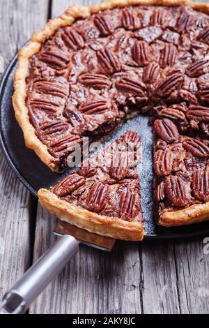Pecan Pie auf einer schwarzen Steinplatte auf einem alten rustikalen Holztisch, vertikale Ansicht von oben Stockfoto