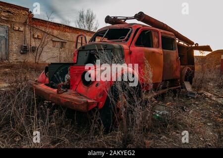 Alter verrostter zerbrochener verlassener sowjetischen Feuerwehrwagen bei Sonnenuntergang am Abend. Stockfoto
