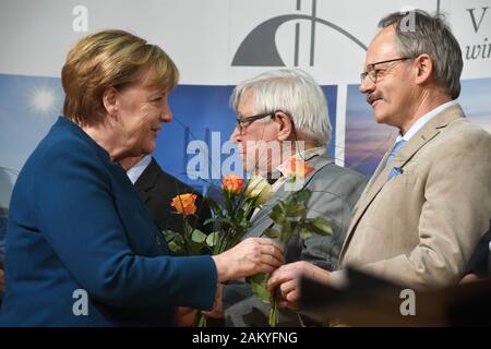 Grimmen, Deutschland. 10 Jan, 2020. Die deutsche Bundeskanzlerin Angela Merkel (l, CDU) präsentiert Die Zustellung der Blumen in Freiwilligen auf dem Neujahrsempfang der Landrat des Vorpommern-Rügen Bezirk. Merkel hat den Wahlkreis Stralsund-Greifswald - Rügen-Vorpommern seit 1990 mit einem Direktmandat im Bundestag vertreten. Quelle: Stefan Sauer/dpa/Alamy leben Nachrichten Stockfoto