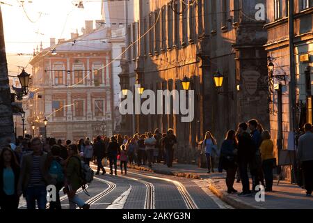 Ukrainische Pendler Spaziergang entlang der Straßenbahn-Linien der alten Stadt in der Dämmerung in Lemberg, Ukraine. Stockfoto