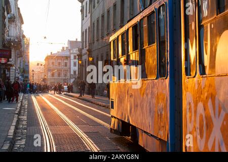 Ukrainische Pendler Spaziergang entlang der Straßenbahn-Linien der alten Stadt in der Dämmerung in Lemberg, Ukraine. Stockfoto