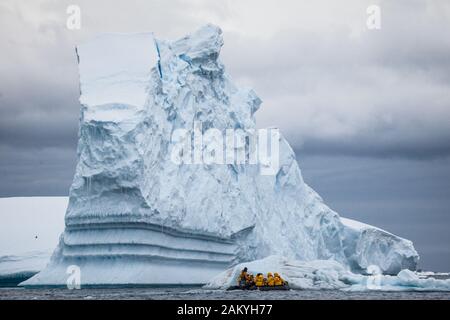 Tierkreis mit Touristen vor einem tabellarischen Eisberg, Antarktis Stockfoto