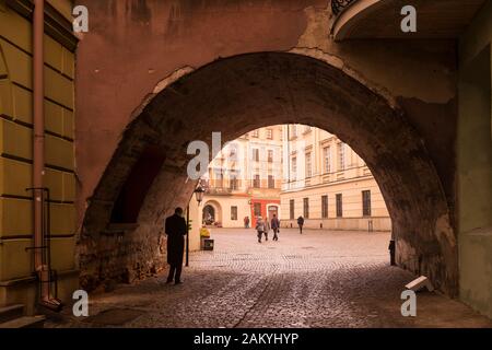 Ein Mann wartet darauf, einen Freund unter einem der vielen Bögen in der Altstadt von Lublin, Polen, zu treffen Stockfoto