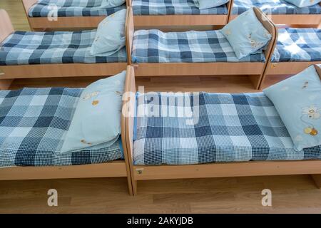 Viele kleine Betten mit frischer Bettwäsche in der Kindertagesstätte Vorschule leere Schlafzimmer Innenraum für komfortable Mittagsschlaf der Kinder. Stockfoto