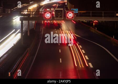 Verkehrssteuerung mit Geschwindigkeitsanzeige bei Nacht, Lichtstreifen von Autos Stockfoto