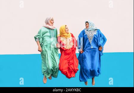 Fröhliche muslimische Mädchen springen zusammen im Freien - arabische Frauen haben Spaß am College - Konzept der Menschen Kultur und Jugend Lifestyle Momente Stockfoto