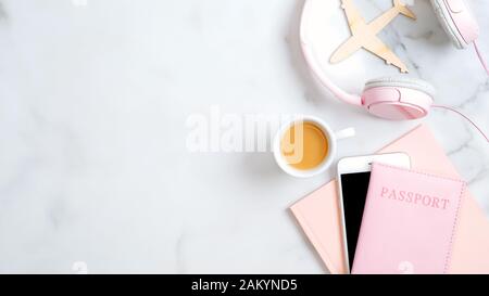 Flat Lay feminines Reisezubehör, Reisepass, Flugzeug, rosafarbener Notizblock, Kaffeetasse, Smartphone auf Marmorhintergrund. Sommerurlaub und Flugreise Co Stockfoto