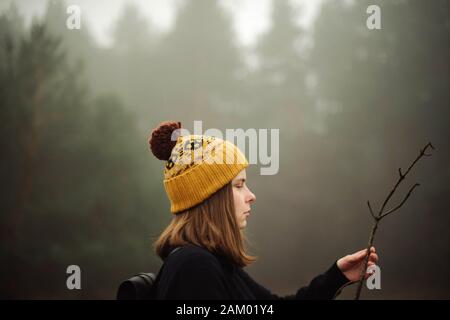 Nachdenkliche Frau, die durch Wald im Nebel Stockfoto