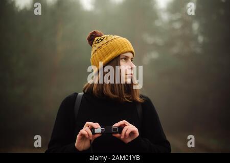 Nachdenkliche Frau, die durch Wald im Nebel Stockfoto