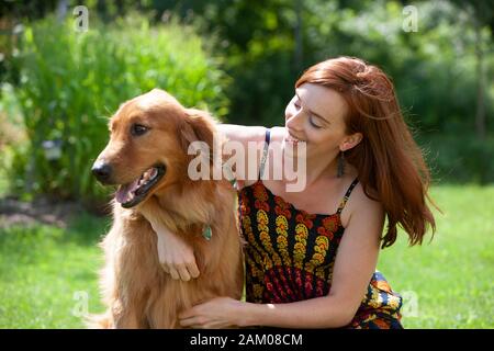 Sommer Porträt einer jungen Frauen mit ihrer dreijährigen Posing - alte Golden Retriever in Ihrem Hinterhof Stockfoto