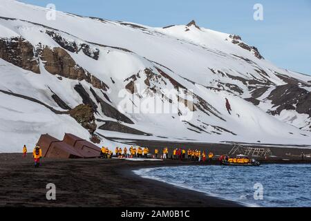 Touristen, die am Strand auf Deception Island, South Shetland Islands, Antarktis, spazieren gehen Stockfoto