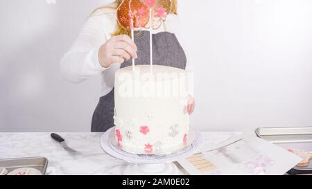 Einfügen von großen Lutscher mit Schneeflocken in den hohen Weiße, runde Kuchen als Dekoration. Stockfoto